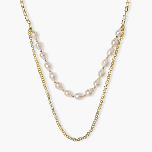 Layered gold chain necklace with organic baroque freshwater pearls and adjustable length on cream background