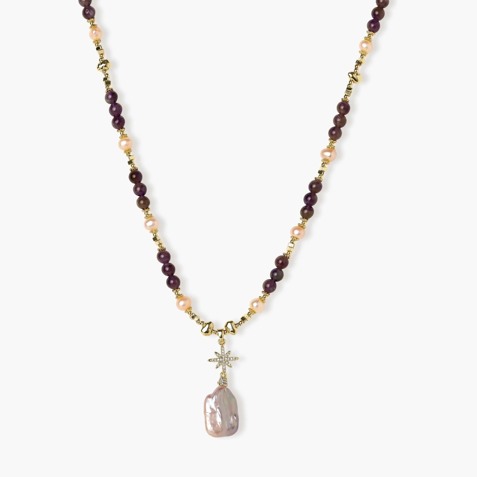 Gold necklace with iridescent baroque pearl pendant, purple amethyst beads, and crystal star charm on cream background